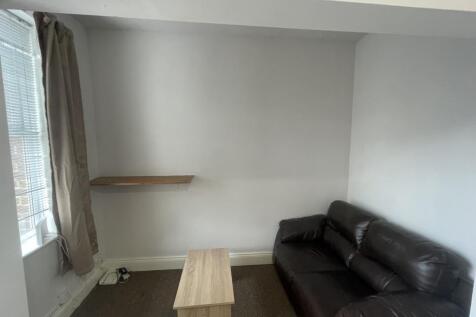 A compact living room featuring a dark leather ...