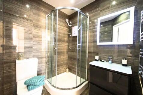 A modern bathroom featuring a sleek curved glas...