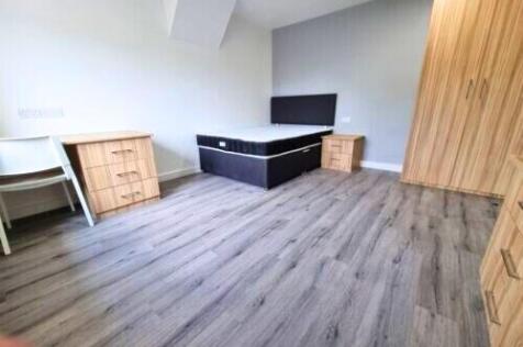 A clean, modern single bedroom featuring wood-e...