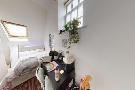 Cozy single bedroom with a skylight and window ...