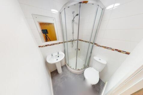 A compact, modern bathroom featuring a curved g...