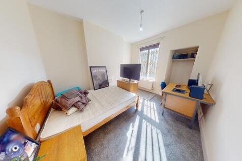 A cozy single bedroom featuring a wooden bed fr...