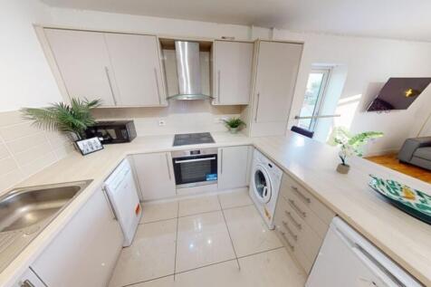 A modern, clean kitchen featuring light counter...