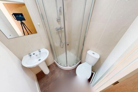Compact and clean bathroom featuring a curved g...