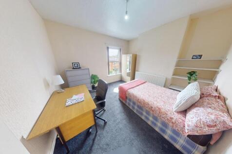 A neat and tidy single bedroom featuring a comf...