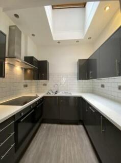 Modern kitchen featuring sleek black cabinetry,...