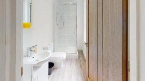 A modern, pristine bathroom featuring a walk-in...