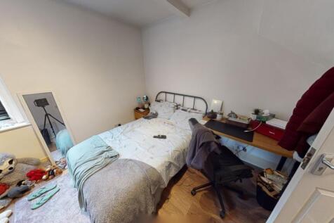 A cozy single bedroom with a neatly made bed, a...