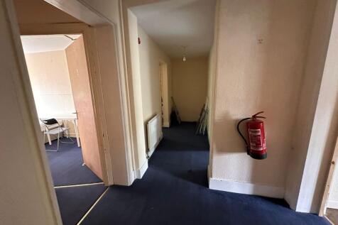 A narrow hallway with dark blue carpet and crea...