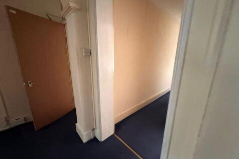 A simple hallway with blue carpet flooring and ...