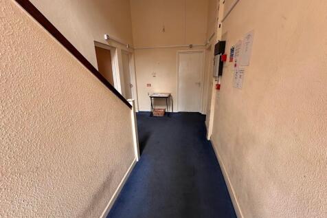 A simple hallway with a blue carpet and cream w...