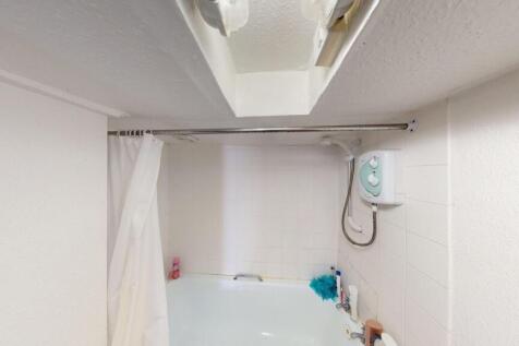 A compact bathroom featuring a bathtub with a s...