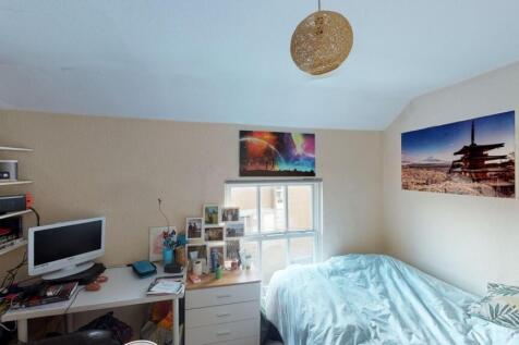 A cozy and well-lit single bedroom featuring a ...