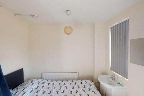 A neat and simple single bedroom with a bed, ra...
