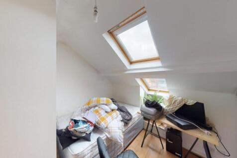 Bright attic room featuring a skylight window t...