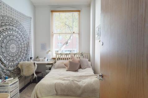 A cozy and well-lit single bedroom featuring a ...