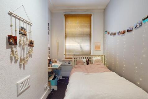 Cozy single bedroom with a neatly made bed, sof...