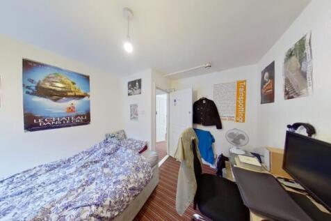 A cozy single bedroom featuring a neatly made b...