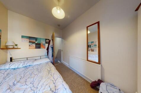 A cozy single bedroom with a neatly made bed, d...