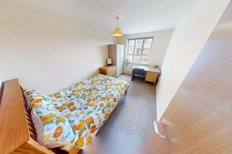 A cozy single bedroom featuring a bed with a co...