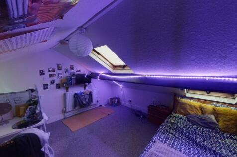 A cozy and stylish attic bedroom featuring a co...