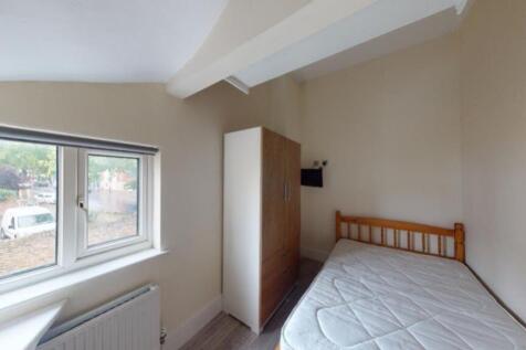 A cozy single bedroom featuring a wooden bed fr...