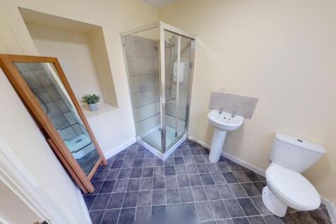 Bright and clean bathroom featuring a corner gl...