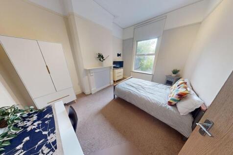 A clean and cozy single bedroom featuring a com...