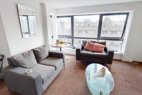 A bright living room featuring large windows th...
