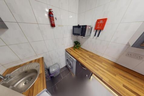 A compact, modern kitchen featuring wooden coun...