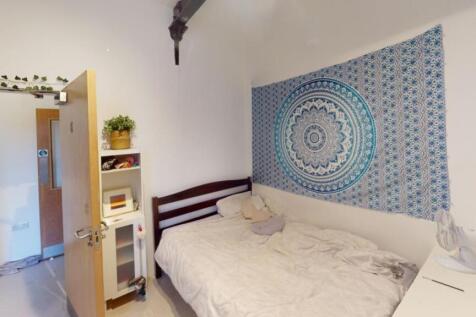 A cozy single bedroom featuring a neat bed with...