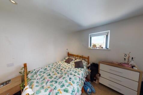 A cozy single bedroom featuring a wooden bed wi...