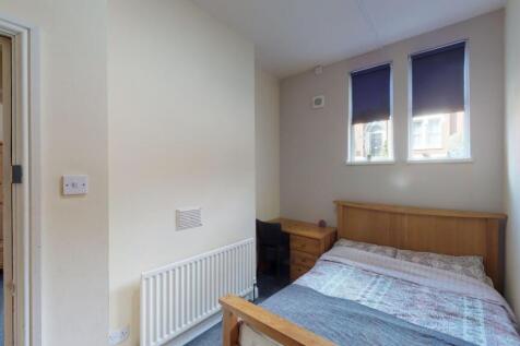 Cozy single bedroom featuring a wooden bed fram...