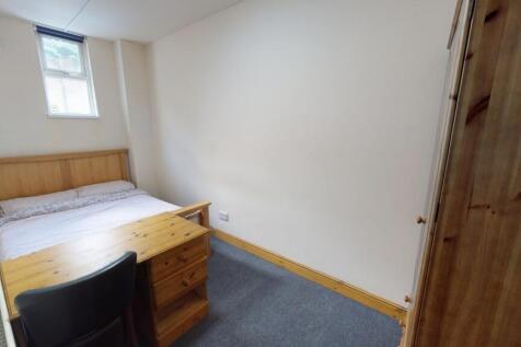 A neat and cozy single bedroom featuring a wood...