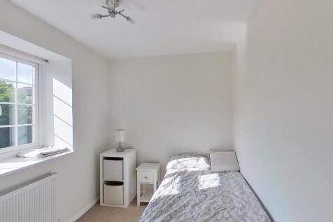 A bright and clean small bedroom featuring a si...