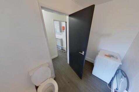 A clean and simple single toilet room with whit...