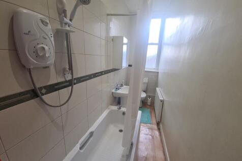 A clean, bright bathroom featuring a bathtub wi...