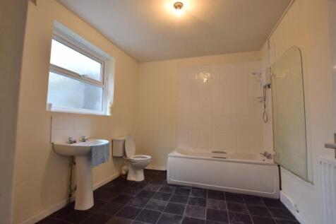 A spacious and well-lit bathroom featuring a ba...
