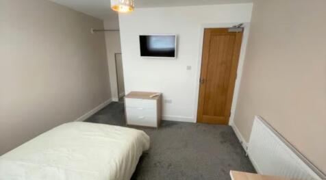 A neat and tidy single bedroom featuring a comf...