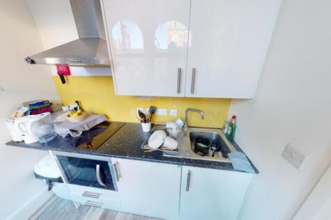 A modern kitchen featuring sleek white cabinets...