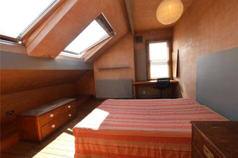 A cozy double bedroom featuring a slanted ceili...