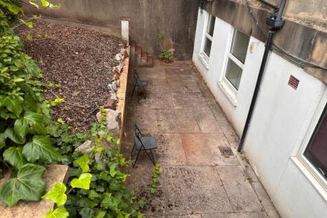 Private paved rear courtyard with two chairs, b...