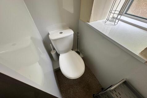 A clean and modern single toilet with ample nat...