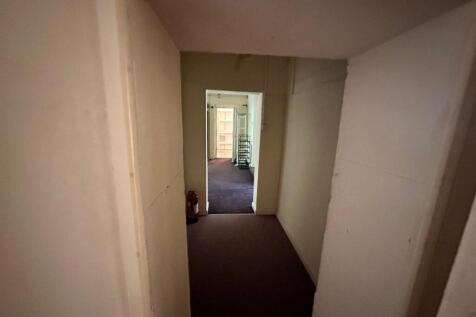 A spacious hallway leading to various rooms, of...