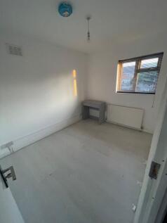 A bright, simple single bedroom with white wall...