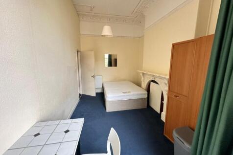 A spacious and inviting double bedroom with cha...