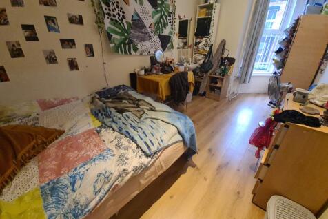 A cozy single bedroom featuring a bright wooden...