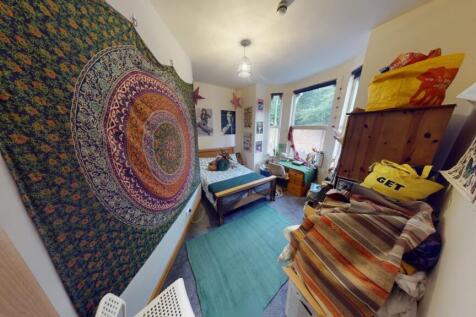 A cozy single bedroom with vibrant wall tapestr...