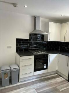 Modern kitchen featuring a sleek black-tiled ba...