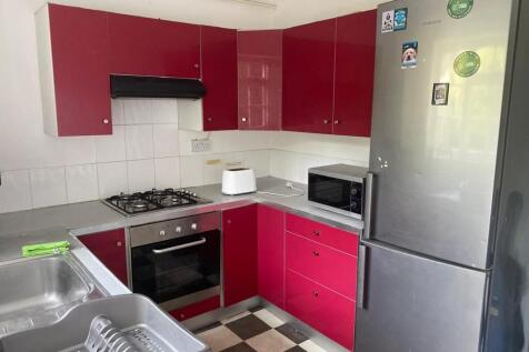 A modern kitchenette featuring vibrant red cabi...